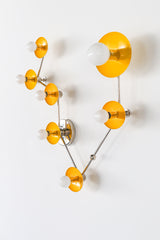 Pisces star sign wall sconce in glossy yellow powder coated steel with polished chrome arms, constellation inspired zodiac light fixture with sculptural round discs and white globe bulbs, modern statement lighting for a small bathroom vanity, powder room over mirror, or playful maximalist decor with a pop of sunny color