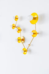 Close angled detail of Pisces constellation light fixture with glossy yellow powder coated steel discs and brass hardware, modern star sign wall sconce with white globe bulbs, statement lighting for a playful bathroom sconce over mirror, artful hallway light, or colorful maximalist home decor with mid century modern vibes