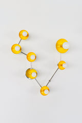 Pisces star sign wall sconce in glossy yellow powder coated steel with polished chrome arms, constellation inspired zodiac light fixture with sculptural round discs and white globe bulbs, modern statement lighting for a small bathroom vanity, powder room over mirror, or playful maximalist decor with a pop of sunny color