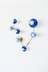 Pisces constellation wall sconce in Mediterranean blue and hydrangea blue with warm brass arms and details, featuring powder-coated steel disc shades and globe bulbs in a star-map inspired layout; bold celestial lighting for a bathroom vanity, powder room, entryway, or bedroom, perfect for eclectic and maximalist interiors, mid century modern style homes, coastal-inspired blues, and anyone who wants a zodiac light fixture that is playful and not basic.