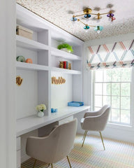 Bright and colorful kids study space with a pisces flushmount ceiling light, wallpapered ceiling, rainbow grid carpeting, and built in shelving.