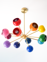 Rainbow sputnik chandelier with glossy multicolor globe shades and warm brass arms, modern mid century ceiling light with red, pink, orange, yellow, green, teal, blue, and purple orbs, playful maximalist statement lighting for a kids bedroom, nursery, playroom, or colorful dining room, contemporary atomic starburst chandelier