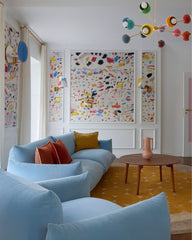 Prism Chandelier in a colorful eclectic living room with baby blue sofas, mustard yellow rug, and bold abstract wall art. Mid-century modern rainbow sputnik light fixture adds dopamine décor energy and vibrant style to contemporary interiors.