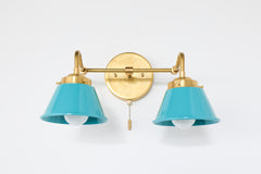 Close-up of brass wall sconce with teal shades featuring a pull chain switch