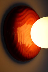 One-of-one sculptural ceramic globe sconce in rich lipstick red with rippled relief surface, matte white globe creating warm ambient illumination and a soft wall glow, modern artisan statement fixture for contemporary interiors, maximalist homes, and design lovers