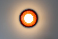 One-of-one sculptural ceramic globe sconce in rich lipstick red with rippled relief surface, matte white globe creating warm ambient illumination and a soft wall glow, modern artisan statement fixture for contemporary interiors, maximalist homes, and design lovers