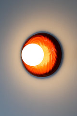 One-of-one sculptural ceramic globe sconce in rich lipstick red with rippled relief surface, matte white globe creating warm ambient illumination and a soft wall glow, modern artisan statement fixture for contemporary interiors, maximalist homes, and design lovers