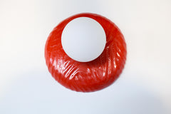 One-of-one handmade ceramic sconce in rich lipstick red with raised wavy relief pattern and a matte white globe, sculptural modern wall or ceiling fixture with hidden hardware, artisan statement lighting for bold color interiors, gallery-style spaces, and contemporary home decor