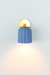 Unglazed soft blue ceramic wall sconce with solid brass hardware, featuring a scalloped silhouette that brings a charming touch to bathroom and powder room lighting; ideal for traditional, coastal, Nantucket-inspired, Southern, or transitional interiors where soft color and timeless form add a refined yet playful focal point.
