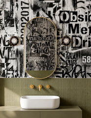 The Sid Sconces bring a little punk-rock attitude to this small bathroom, with glossy black backplates, gold spike details, and exposed globe bulbs. The black-and-white collage wallpaper, olive tile wainscoting, brass mirror, and sculptural white sink create a high-contrast powder room with a playful edge.