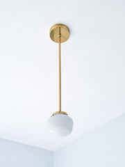 There's a particular magic when brass hardware meets schoolhouse glass—a conversation between collected vintage and intentional design. The petite dome of this shade has presence despite its compact size, mounted on a warm brass rod that catches light like jewelry. Imagine a hallway lined with these, or a powder room where every detail matters. The schoolhouse form, with its structured silhouette and architectural presence, becomes a collector's detail—the kind of fixture that makes visitors pause and ask w