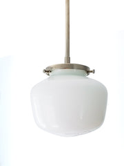 This is the fixture for the kitchen you actually want to cook in—where efficiency meets aesthetic grace. The schoolhouse glass shade, suspended clean from a brushed nickel canopy, creates an almost Scandinavian clarity: form following function, nothing wasted, everything essential. The gently rounded dome catches and diffuses light with architectural intention, casting a gentle wash across counters and workspace. There's an honesty to this pendant that contemporary kitchens crave—the compressed dome silhoue
