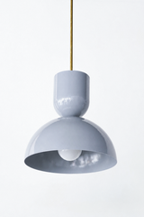 Soft grey is the cool neutral that grounds a kitchen without going cold, and this Taeuber pendant keeps it looking considered rather than plain. The two-part silhouette stacks a rounded cup over a wide domed bell, all finished in a glossy slate grey with a warm brass stem, shown here lit and glowing. The cool tone plays beautifully against brass, marble, wood, and any color you bring in elsewhere, bringing a quiet, sophisticated edge over an island, breakfast nook, or sink. Hang one for subtle contrast or a