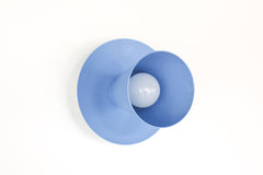 Modern & Geometric Color Saturated wall sconce or ceiling flushmount light fixture shown in pastel blue but available in over 30 curated colors.  Make a bold statement as bathroom wall lighting or in a small space as a ceiling light.  Consists of a geometric cone shade.  Maximalist and chunk wall sconce or ceiling light fixture in bold colors perfect for color-lovers, minimalists that embrace color, kids spaces, and more.  The Sonny sconce is designed and made in New Orleans.