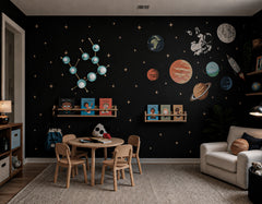 Space-themed kids playroom with the Poolside and Brass Gemini One sconce mounted on a black galaxy wall covered in stars, planets, an astronaut, and a rocket. The constellation-shaped wall light has soft aqua Poolside discs, brass rods, and white globe bulbs, tying into the celestial room theme. A wood kids table, low bookshelves, reading chair, textured rug, and playful space decor make this feel perfect for a modern playroom, nursery, Montessori room, kids reading nook, or astrology-inspired bedroom.