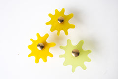 Multiple Splat drawer pulls in various finishes like glossy yellow, yellow pearl, and frosted yellow arranged on a white background, showcasing their versatility and playful character.
