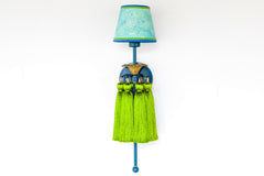 Full view of the Tropical Tasseled Wall Sconce with lagoon blue frame and backplate, antique brass floral accent, lush chartreuse green silk tassels, and a custom hand-marbled aqua and green shade. This bold midcentury-inspired wall light brings a pop of color and tropical personality to eclectic or maximalist decor.