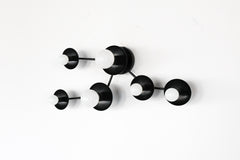Mid-century modern black constellation wall sconce inspired by Taurus, featuring multiple star discs connected in a clean, geometric pattern. A statement wall light for contemporary interiors, eclectic homes, and modern design spaces. Handmade to order in New Orleans by Sazerac Stitches. Ideal for bedrooms, foyers, hallways, and feature walls.