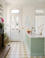 Celestial blue Taurus constellation wall sconce with brass arms and white globe bulbs, installed in a bright kitchen entryway near the front door. Modern astrology lighting that reads like sculptural wall art and adds a mid-century modern pop of blue.
