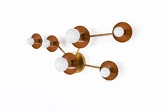 Taurus wall fixture in Fudge and brass with a constellation-inspired layout, mixing small and large circular star discs with glowing white bulbs. Ideal for a moody bedroom, masculine office, warm modern living room, or artful staircase wall.