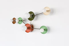 Taurus wall fixture in earthy tones with chrome arms, featuring brown, mint, olive, cream, and terracotta circular discs with globe bulbs. A sculptural constellation-inspired light for eclectic, organic modern, and color-forward interiors.