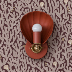 A warm terracotta shell sconce melting into an earthy coral-print wallpaper — a tonal, dialed-back take on coastal that skips the cliché. The Coquille from Sazerac Stitches is a scallop-shell wall light in a matte terracotta finish with a warm brass fitting and scalloped floral backplate, set against a burgundy-and-blush wallpaper scattered with coral branches and little shells. Quietly moody, perfect for a warm-toned bathroom, an earthy bedroom, or a grown-up coastal powder room. Works for terracotta decor