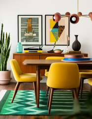 Modern dining room with the Terra Cotta & Brass Arcenciel chandelier, a sculptural mid-century inspired light with globe shades, suspended above a walnut dining table surrounded by mustard yellow chairs. The warm and colorful space includes abstract artwork, a zigzag green rug, mid-century sideboard, and houseplants, showcasing eclectic retro style with handmade statement lighting.