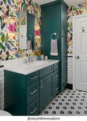 Doll pink and brass double globe wall sconce mounted beside a mirror in a bold maximalist powder room with colorful patterned wallpaper, teal vanity cabinetry, and vintage inspired finishes, a playful statement bathroom sconce for eclectic interiors and fun modern design.