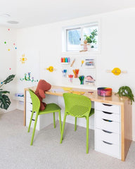 Kids’ study desk with Thalia Sconces in yellow by Sazerac Stitches, bright green chairs, pegboard storage, and colorful art supplies.