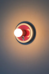 Colorblocked pink and white wall sconce with a chrome toggle on-off switch
