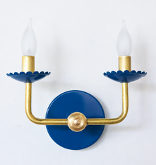 A classic two-arm candle sconce takes on a confident cobalt blue here, with scalloped bobeche cups beneath frosted flame-tip bulbs and traditional curved brass arms. It is the kind of colorful lighting that fits a Southern traditional or grandmillennial room without straying from a familiar, classic shape.