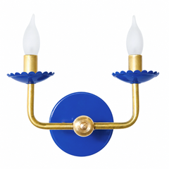 A classic two-arm candle sconce takes on a confident royal blue here, with scalloped bobeche cups beneath frosted flame-tip bulbs and traditional curved brass arms. It is the kind of colorful lighting that fits a Southern traditional or grandmillennial room without straying from a familiar, classic shape.