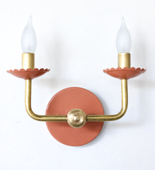 This two-light brass wall sconce takes the classic candle-sconce shape into warmer, earthier territory, with scalloped bobeche cups powder-coated in a sun-washed terracotta beneath frosted flame-tip bulbs. The curved brass arms keep it traditional, while the clay-orange color feels grounded and collected rather than sweet, good for a dining room, entryway, or Southern traditional space that wants warmth.