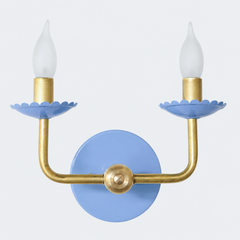 This one sits softer than the other blues already in this line, a periwinkle that leans slightly lavender rather than anything true or navy. The scalloped bobeche cups and backplate carry that gentle color while the raw brass arms keep the same clean, modern posture underneath. It has a French bedroom or nursery quality to it, sweet without tipping into saccharine, the kind of soft color that would sit nicely against toile, a floral quilt, or a grandmillennial-leaning guest room.