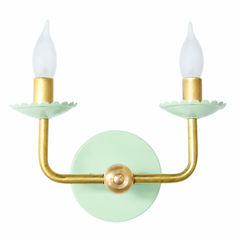 This one has the pale, porcelain quality of an old celadon ginger jar rather than anything grass green or minty bright. Set on the same clean, U-shaped raw brass arms as the rest of the line, it keeps a modern posture even while the scalloped bobeche cups and candlelight-shaped bulbs stay firmly traditional. The color feels garden-adjacent and a little English, the kind of soft green that would sit happily against chinoiserie wallpaper, a cottage-leaning bedroom, or a breakfast nook with botanical prints, w