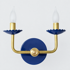 This one goes darker and more classic than the brighter blues in the line, a deep navy on the scalloped bobeche cups and backplate that reads coastal traditional rather than playful. The raw brass arms keep their clean shape, so it still fits comfortably next to the rest of this collection while offering a quieter, more grounded color option.