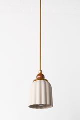 unglazed cream porcelain shade with glossy chocolate brown and brass accents. the pendant shade has a ribbed shape and unglazed. Includes a powdercoated ball and brass hardware accents. Modern and handmade in New Orleans by Sazerac Stitches.