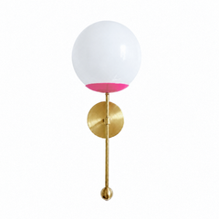 A punchy hot-pink globe sconce for a powder room, girl's room, or bedside that wants a wall light with real personality. The Verbena Sconce tops a round brass backplate with a slim brass stem, seats a white glass globe in a bright doll-pink cup, and finishes the bottom with a small brass ball, the kind of detail that makes it feel custom. Hot pink and brass together read flirty and fearless, the most high-voltage pink in the line, striking flanking a mirror, art, or a bed. A joyful, glowing light for maxima