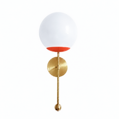 A fiery flame-orange globe sconce for a powder room, bar, or bedside that wants a wall light with real warmth and punch. The Verbena Sconce tops a round brass backplate with a slim brass stem, seats a white glass globe in a bright orange-red cup, and finishes the bottom with a small brass ball, the kind of detail that makes it feel custom. Flame and brass together read bold and high-energy, striking flanking a mirror, art, or a bed, especially against a moody or warm-toned wall. A joyful, glowing light for 