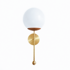 A warm caramel-brown globe sconce for a powder room, bedside, or hallway that wants a wall light with quiet, earthy richness. The Verbena Sconce tops a round brass backplate with a slim brass stem, seats a white glass globe in a soft fudge-brown cup, and finishes the bottom with a small brass ball, the kind of detail that makes it feel custom. The brown cup sits close in tone to the brass for a warm, tonal look, lovely flanking a mirror, art, or a bed, especially against cream walls, wood, or a moody paint 