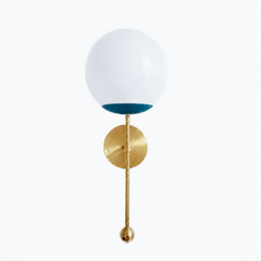 A moody lagoon-teal globe sconce for a powder room, study, or bedside that wants a wall light with some depth to it. The Verbena Sconce tops a round brass backplate with a slim brass stem, seats a white glass globe in a deep teal cup, and finishes the bottom with a small brass ball, the kind of detail that makes it feel custom. This dusky blue-green and brass together read grown-up and a little coastal, lovely flanking a mirror, art, or a bed, especially against dark walls, warm wood, or collected antiques.