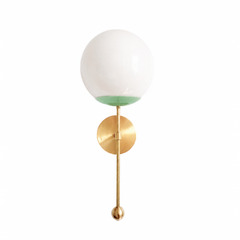 A crisp apple-green globe sconce for a powder room, kitchen, or bedside that wants a wall light with fresh, garden-happy color. The Verbena Sconce tops a round brass backplate with a slim brass stem, seats a white glass globe in a soft vista-green cup, and finishes the bottom with a small brass ball, the kind of detail that makes it feel custom. This lively green and brass together read fresh and cheerful, lovely flanking a mirror, art, or a bed, especially against white trim, botanical wallpaper, or natura