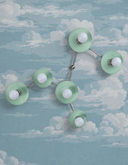 Dreamy blue cloud wallpaper creates a playful celestial backdrop for the Virgo sculptural wall sconce in Mint with Chrome hardware. Six round concave shades and globe bulbs trace the Virgo zodiac constellation, turning modern wall lighting into functional wall sculpture. This soft blue and mint palette offers whimsical wallpaper inspiration for a nursery, child’s bedroom, imaginative powder room, or eclectic interior. Discover customizable constellation lighting by New Orleans studio Sazerac Stitches.