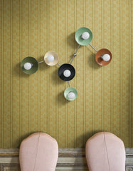 Green patterned wallpaper, blush upholstered chairs, decorative wall molding, and a multicolor Virgo wall sconce create an unexpected mix of traditional elegance and colorful modernism. The customizable Sazerac Stitches light features Olive Green, Cream, Black, Mint, Vista Green, and Fudge Brown concave shades connected by Chrome arms in the shape of the Virgo constellation. A distinctive idea for statement lighting, maximalist dining rooms, boutique interiors, and eclectic green-and-pink decorating schemes