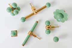 Collection of vista green and brass cabinet hardware including a multi-ball cluster knob, a long double-ball cross-bar pull, a bar pull, a scalloped flower knob, a single ball knob, and a small double gumball knob, versatile colorful options for furniture makeovers, bathrooms, built-in cabinets, kitchens, kids' rooms, and offices.