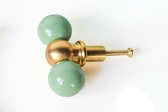 Vista green and brass double gumball knob, shown at an angle. A versatile colorful knob that suits dresser makeovers, colorful bathrooms, kitchen cabinetry, built-ins, kids' spaces, and offices alike.