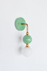 A glossy sage-green wall sconce for a bathroom, powder room, or bedroom that leads with calm, easy-to-live-with color. The Ida sconce stacks a muted green powder-coated sphere over a frosted glass globe, joined by warm brass hardware and a round green backplate. Soft, soothing, and gently confident, it's a standout for eclectic, English cottage, coastal traditional, and colorful traditional homes that skip the safe answer.