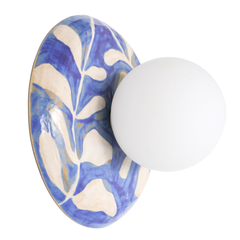 Side view of a one-of-one handmade ceramic globe wall sconce showing the sculptural curved ceramic backplate with glossy blue and white leafy watercolor pattern and a matte white globe shade, artisan pottery lighting with a clean modern profile for designer interiors, bedside sconces, hallway lighting, and statement wall fixtures
