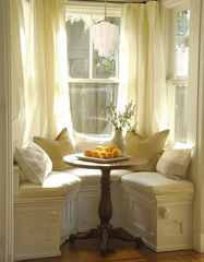 Wedding Cake Pendant Light in glossy white with brass stem, styled in a traditional breakfast nook with built-in banquette seating, round pedestal dining table, cream cushions, flowing white curtains, and neutral layered pillows. Bright and airy small dining corner with farmhouse-inspired details and natural light — custom handmade Art Deco pendant lighting by Sazerac Stitches, perfect for breakfast nooks, kitchens, and intimate dining spaces.