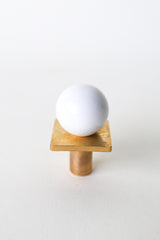 Glossy white and brass square gumball knob for cabinets, drawers, and furniture. Modern round cabinet pull with a minimalist twist. Perfect for kitchens, kids rooms, nurseries, or bathrooms. Adds a crisp, playful detail to colorful or neutral interiors with midcentury modern flair.